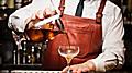 bartender pours a cocktail at an upscale speakeasy bar. North America.