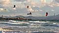 Kitesurfing in Tarifa. Plenty of colorful kites flying against a background of the mountains, beautiful clouds and waves of the Atlantic Ocean