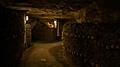 Pathway in catacombs. Old skulls and bones form walls. Grim lighting. Underground cemetery.