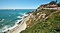 Colorful city sits atop a hill next to the ocean with road below in Mazatlan. Mexico.