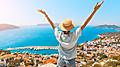 Happy woman with open arms stands on the viewpoint and enjoys the panorama of Kas resort town of the Mediterranean sea in Turkey