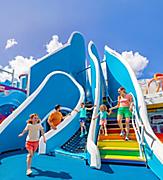 WN, Wonder of the Seas, family fun at Playscape, daytime, mother and daughter on stairs, one child running, dad watching daughter on ropes, blue colors, octopus statue in right background,